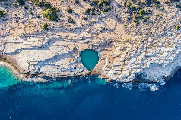 top-down-aerial-view-of-giola-lagoon-in-thassos-a-natural-heart-shaped-rock-pool-surrounded-by-dramatic-rocky-cliffs-and-vibrant-blue-green-sea-waters1BD46B99-9CA2-6C6A-12FA-D9CA5FA70737.webp