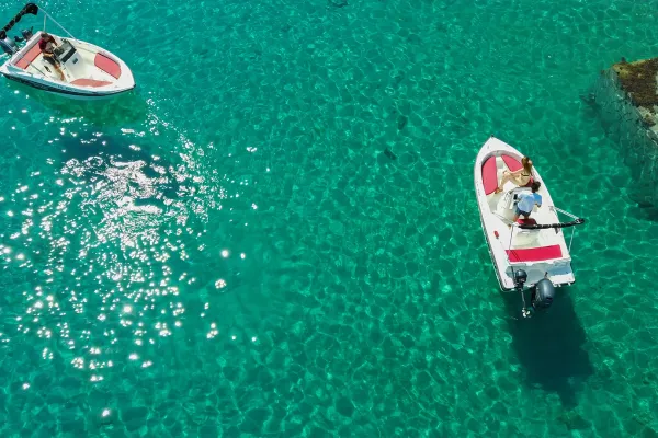 aerial-view-of-two-real-holidays-rental-motorboats-exploring-the-sparkling-crystal-clear-waters-of-thassos-near-rocky-shores-1BAB02AF6-8AE3-96F4-6DAD-98C179421226.webp