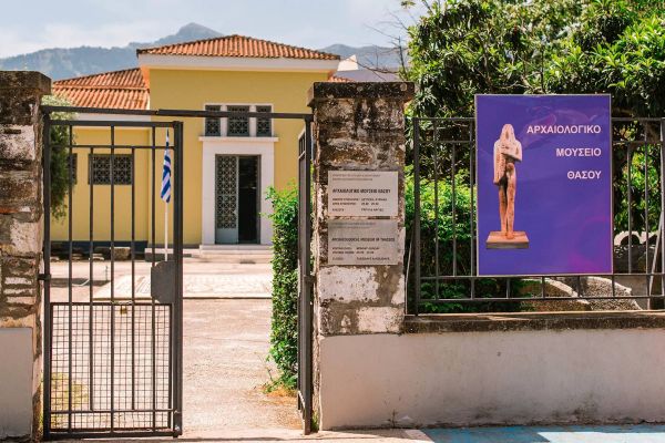 entrance-gate-to-the-archaeological-museum-of-thassos-featuring-a-sign-with-museum-hours-and-a-poster-of-a-sculpture-136D76F24-DF41-22AC-EDB9-7790993879C3.jpg